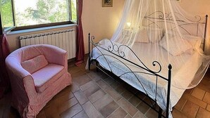 A bedroom with a bed under a canopy, a chair, a window with curtains, and a ceiling fan. - Villa Gramigna: A charming two-story villa surrounded by the greenery. (Pontecuti)