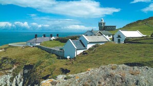 A coastal village with white houses, a lighthouse, and a view of the sea. - This cottage is part of the Bull Point Lighthouse site, just outside the pretty village of Mortehoe. (Woolacombe)