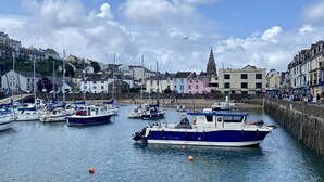 A harbor with boats docked, a church, and a hotel named "The Royal Britannia Hotel" in the background. - This cottage is part of the Bull Point Lighthouse site, just outside the pretty village of Mortehoe. (Woolacombe)