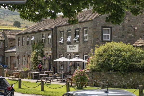 Un edificio de piedra con un letrero que dice "Wharfview Tea Room" y mesas al aire libre con sombrillas.