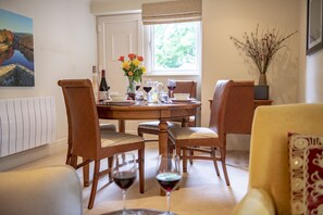 A dining area with a wooden table, four chairs, and a vase of flowers.