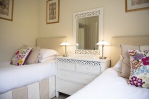 A hotel room with two beds, a dresser, and a mirror.