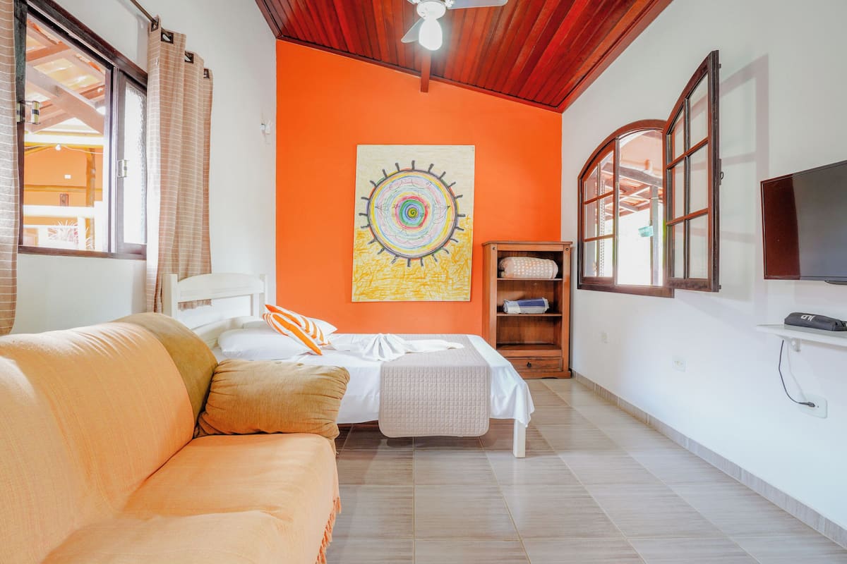 Quarto com cama, sofá, armário de madeira e televisão.