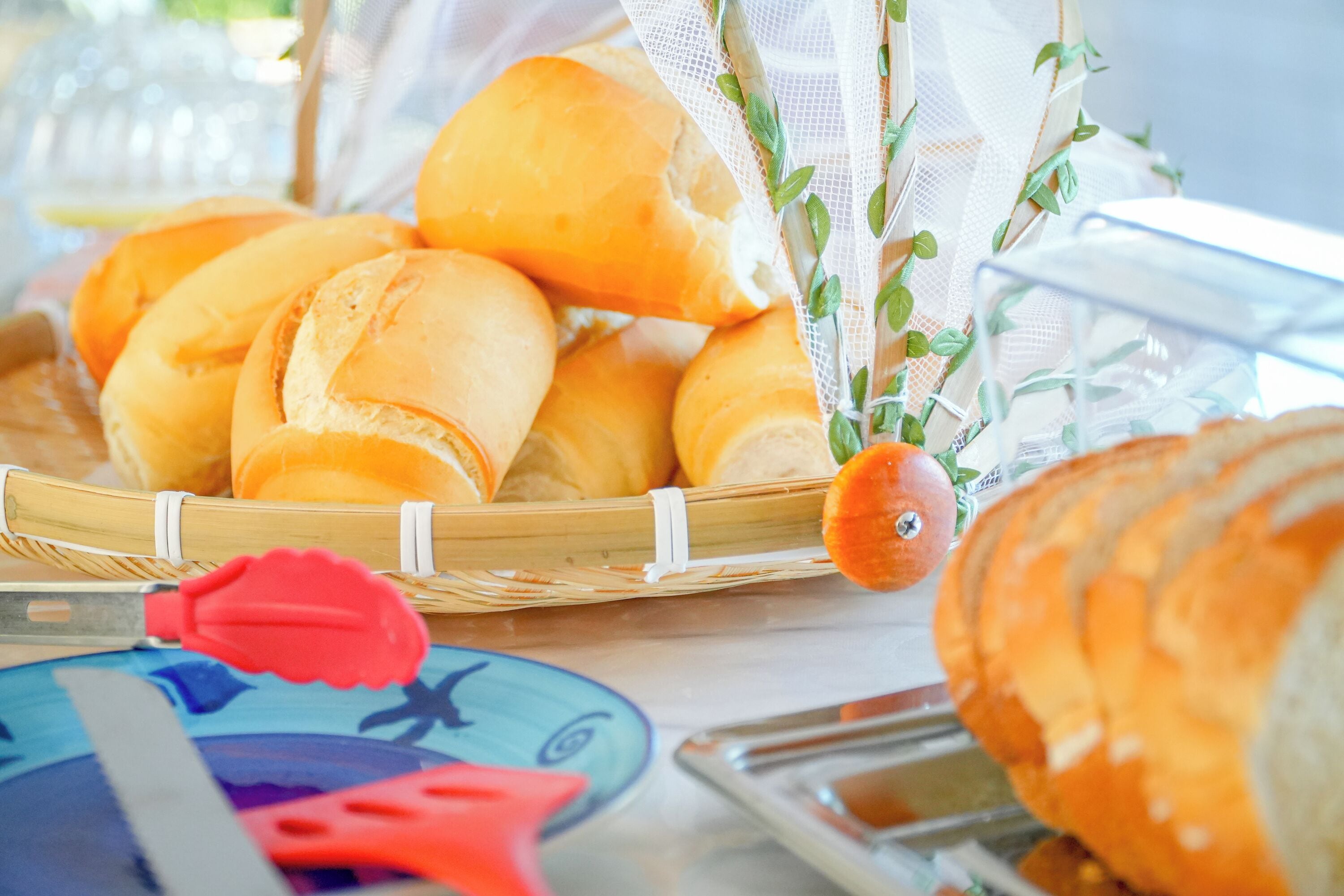 A basket of bread rolls on a table with a decorative orange and greenery.
