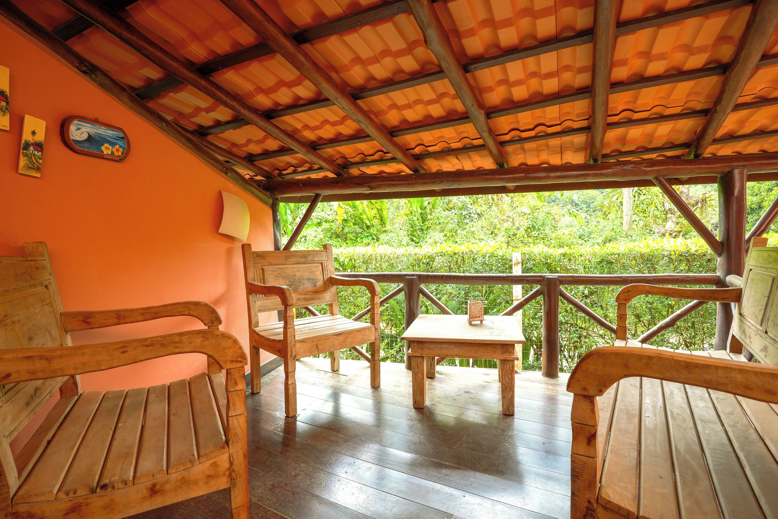 A wooden deck with benches and a table, surrounded by orange walls and a wooden ceiling.