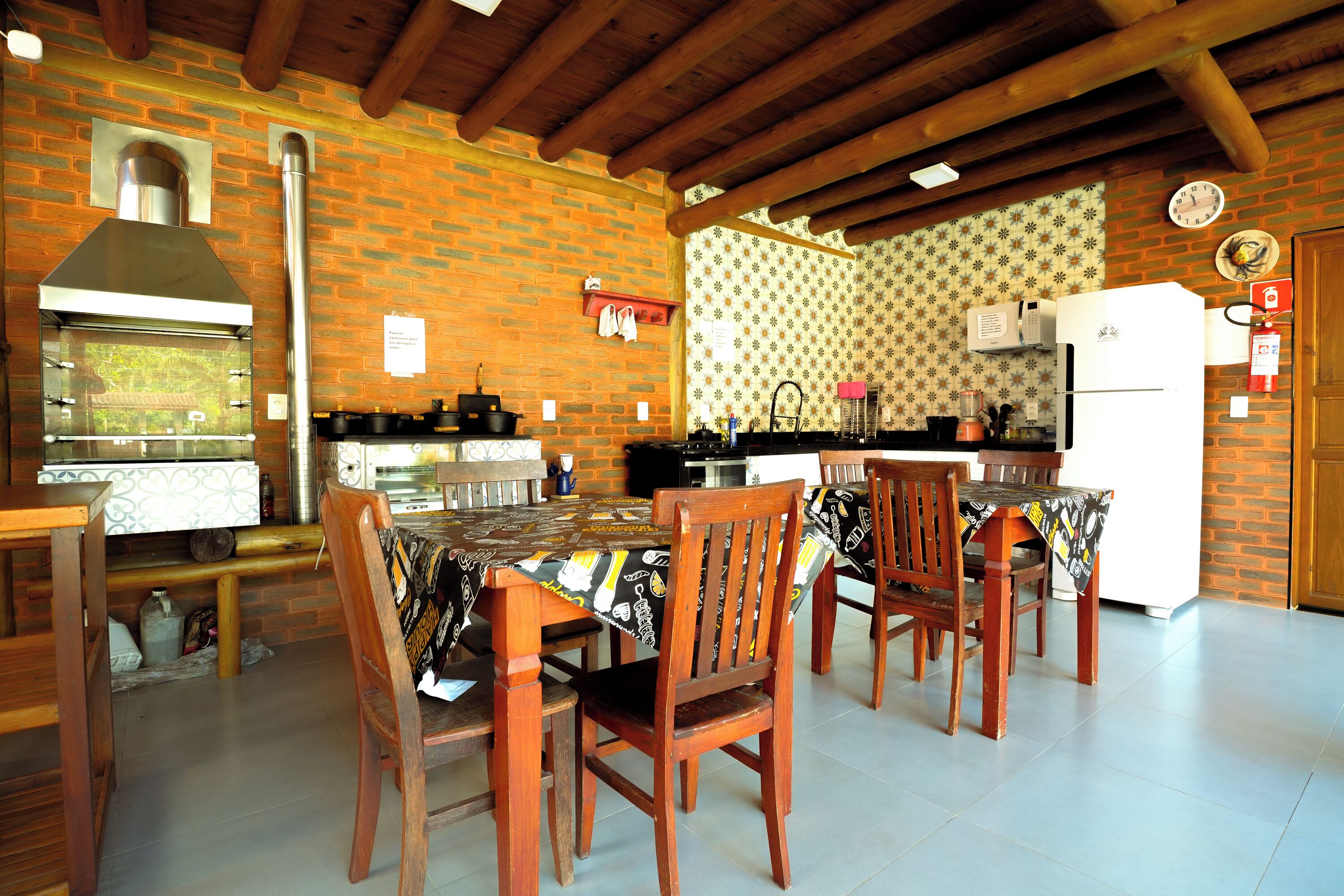 Uma cozinha com paredes de tijolo, teto de madeira e um espaço de jantar com cadeiras e mesa de madeira.