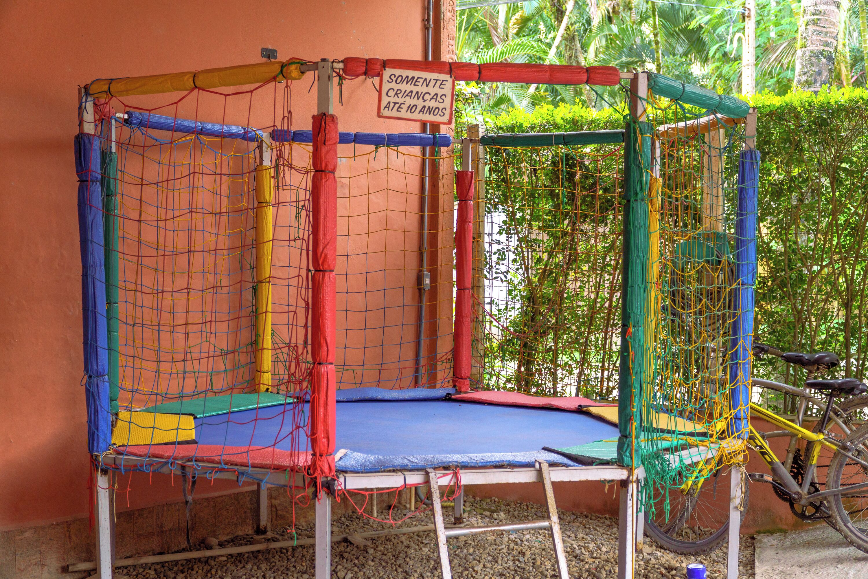 Un trampolín con red de seguridad y un letrero que indica que es para niños menores de 10 años.