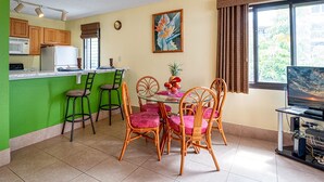 Un espacio habitable compacto con kitchenette, comedor y televisor.
