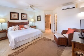 Une chambre d’hôtel dotée d’un grand lit, d’un coin salon avec des meubles en osier et d’un téléviseur.