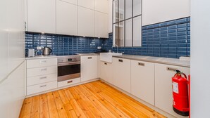 Een moderne keuken met witte kastjes, een roestvrijstalen oven en een blauwe tegelachtergrond.