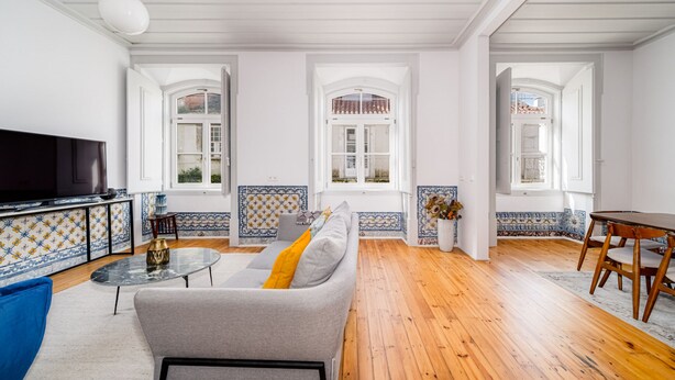 Een woonkamer met een bank, televisie en een eethoek met een tafel en stoelen.