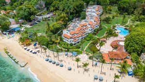 A resort with a beach, a pool, and a building with multiple balconies. - Poolside condo on beautiful beach - Glitter Bay 412 (Porters)