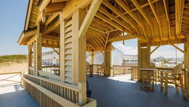 A wooden deck with outdoor seating and a view of the beach. - CR102 - Sea La Vie by First Flight Rentals (Kill Devil Hills)