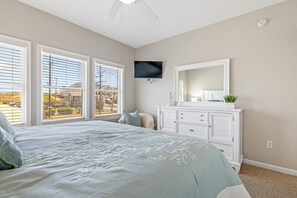 Ein Schlafzimmer mit Bett, Kommode, Fernseher und Blick ins Freie.
