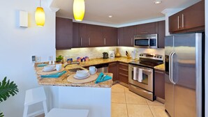 Une cuisine moderne avec des meubles de couleur brun foncé, des appareils en acier inoxydable et un plan de travail en granit.