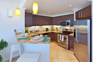 Una cocina moderna con gabinetes marrón oscuro, electrodomésticos de acero inoxidable y encimera de granito.