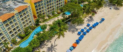 Een resort met een zwembad, strand en meerdere balkons.