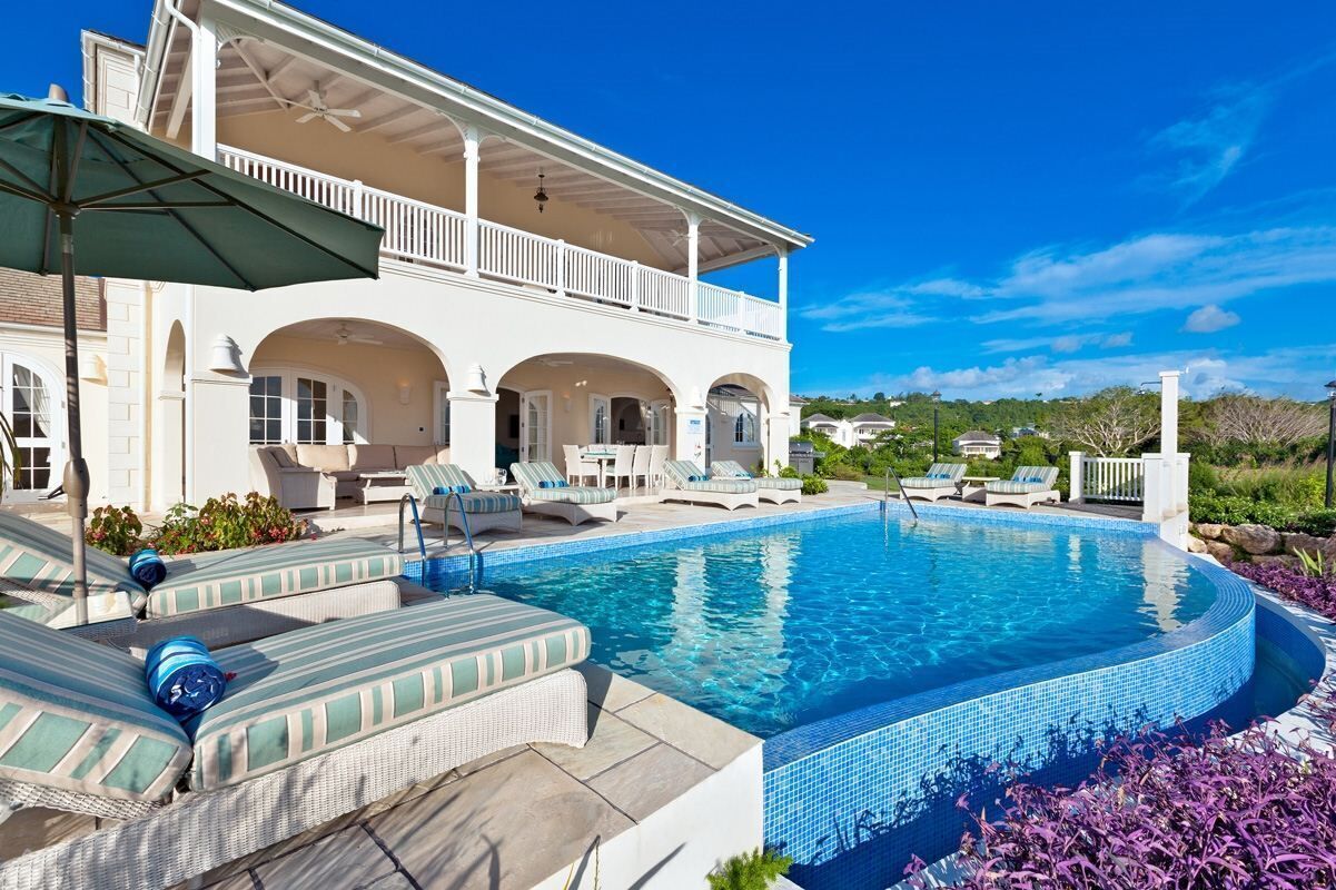 A pool area with lounge chairs and a covered patio.