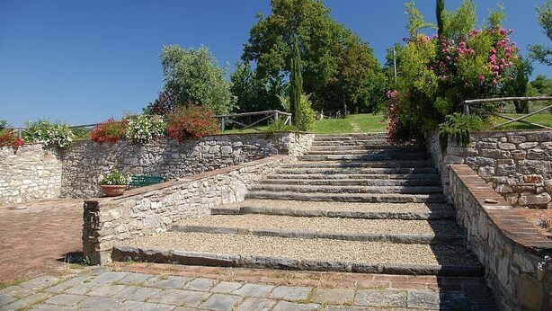 A stone staircase leading up a hill, surrounded by lush greenery and flowering plants. - Casa Bonannia A: A cheerful one-story apartment in the characteristic style of the Tuscan countryside. (Bagno a Ripoli)