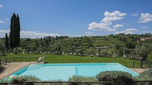 A swimming pool with lounge chairs and a view of a green landscape with trees and hills. - Casa Bonannia A: A cheerful one-story apartment in the characteristic style of the Tuscan countryside. (Bagno a Ripoli)