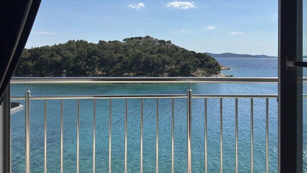 A balcony with a view of a clear blue sea and a small island with dense greenery. - Studio apartment in Tribunj with Seaview, Balcony, Air condition, WIFI (68-1) (Tribunj)