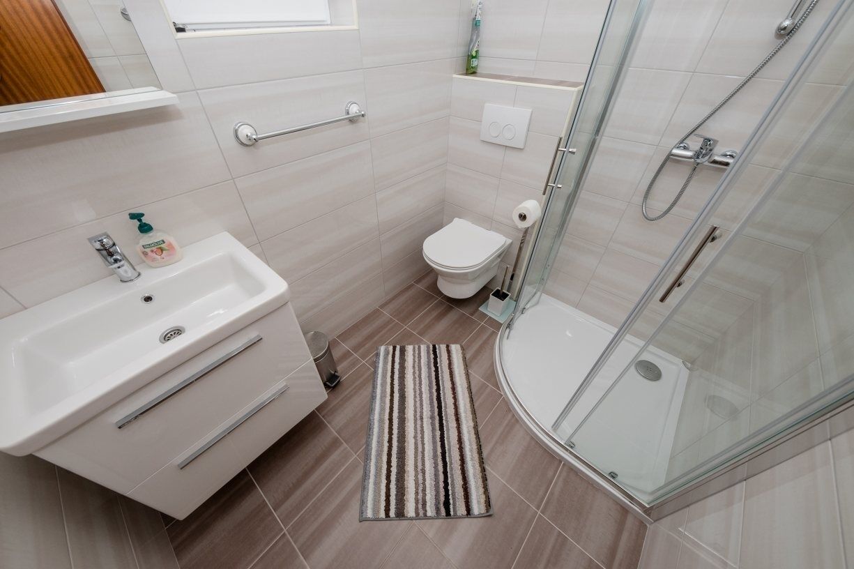 Une petite salle de bain moderne, équipée d’un lavabo, de toilettes et d’une douche à parois de verre.