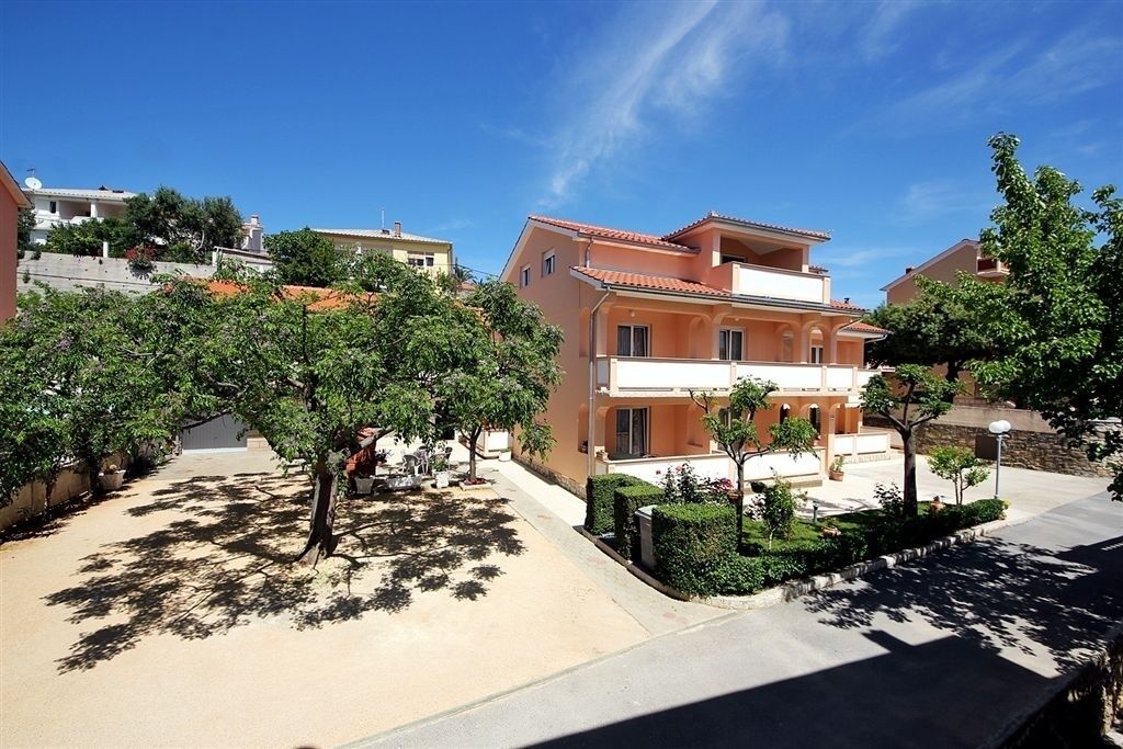 A residential building with a two-story structure, a balcony, and a paved driveway.