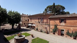 Un patio con una fuente, plantas en macetas y un edificio con tejado de azulejos.