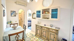 Comedor con mesa, sillas, una lámpara de araña y un aparador con objetos decorativos.