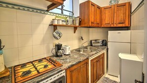 Una cocina con armarios de madera, estufa a gas, un lavaplatos y un refrigerador.
