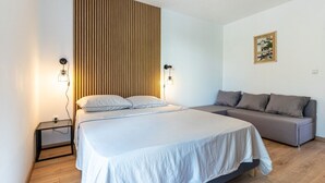 A modern bedroom with a large bed, a grey sofa, and two wall-mounted lamps. - Apartment in Cres with Balcony, Air condition, WIFI, Washing machine (4249-2) (Cres)