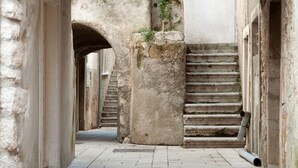 A narrow stone corridor with a staircase leading upwards, flanked by walls and an archway. - Apartment in Cres with Balcony, Air condition, WIFI, Washing machine (4249-2) (Cres)