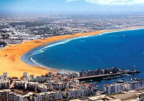 A coastal cityscape with a beach, buildings, and a marina.