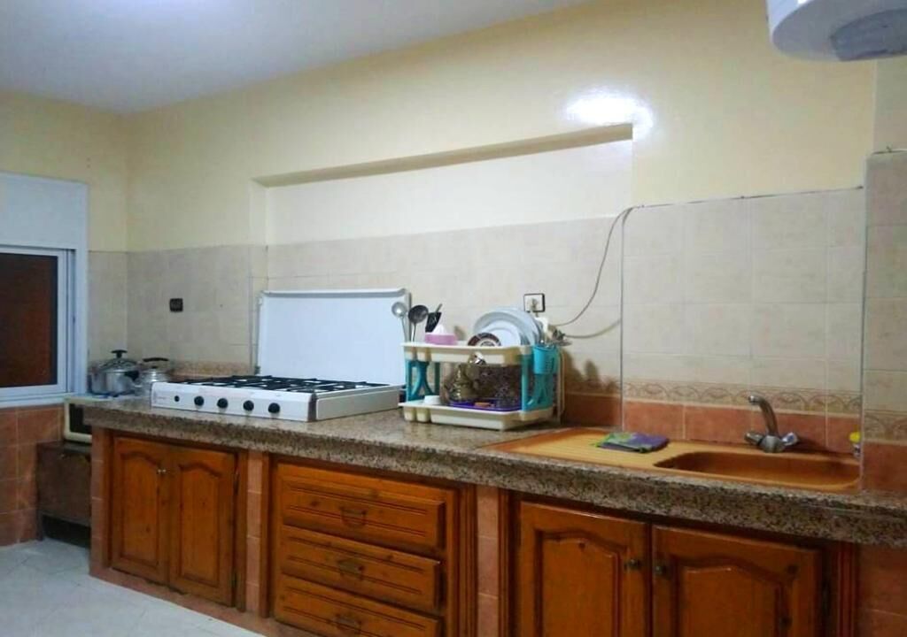 A kitchen with wooden cabinets, a gas stove, a sink, and a dish rack.