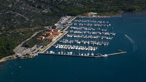 An aerial view of a marina with numerous boats docked, surrounded by hilly terrain and sparse vegetation. - Apartment in Stivan with Terrace, Air condition, WIFI (920-2) (Stivan)