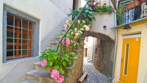 A narrow stone staircase with pink flowers, a wooden bench, and a yellow door. - Apartment in Baška with Terrace, Air condition, WIFI, Washing machine (863-3) (Baška)