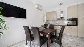 A modern kitchen with a dining area, featuring a flat-screen TV, air conditioning, and a built-in oven. - Apartment in Duće with Seaview, Terrace, Air condition, WIFI (3423-3) (Duce)