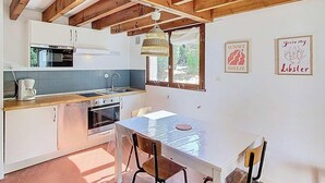 A kitchen with wooden beams, a dining table, and two framed pictures on the wall.
