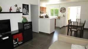 A modern living room with a flat-screen TV, a sofa, and a dining area with a table and chairs. - House 3 bedrooms, 6 people in a residence with pool in Lacanau ocean (LACANAU OCEAN)
