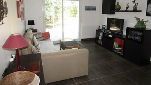 A living room with a sofa, a TV, a lamp, and a dining table. - House 3 bedrooms, 6 people in a residence with pool in Lacanau ocean (LACANAU OCEAN)