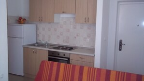 A compact kitchen with wooden cabinets, a white refrigerator, and a tiled backsplash. - Apartment in Vodice with Terrace, Air condition, WIFI (3599-7) (Vodice)