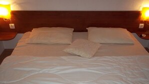 A neatly made bed with a white duvet and two pillows, flanked by two bedside lamps on wooden nightstands. - Apartment in Vodice with Terrace, Air condition, WIFI (3599-7) (Vodice)