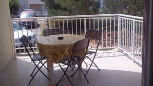 A balcony with a round table and four chairs, a railing, and a view of parked cars and trees. - Apartment in Vodice with Terrace, Air condition, WIFI (3599-7) (Vodice)