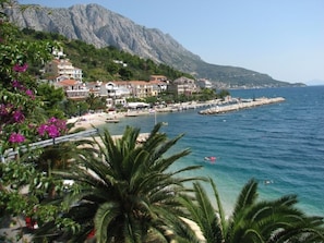 A coastal town with buildings along the waterfront, a pier, and a mountainous backdrop.