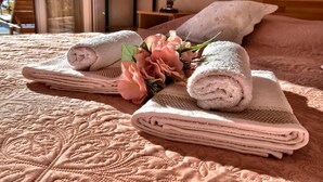 Un letto rifatto con asciugamani piegati e un composizione floreale.