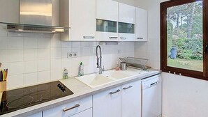 A modern kitchen with white cabinets, a stainless steel range hood, a double sink, and a dishwasher. - Charming house with garden in the pine forest for 6 people in Lacanau Ocean (LACANAU OCEAN)
