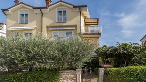 Un immeuble résidentiel de deux étages doté d’un balcon, d’un mur en pierre et d’une porte.