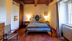 A bedroom with a bed, wooden bench, and a radiator.