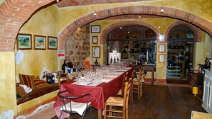A restaurant with a long table set for dining, brick arches, and wine bottles on shelves.