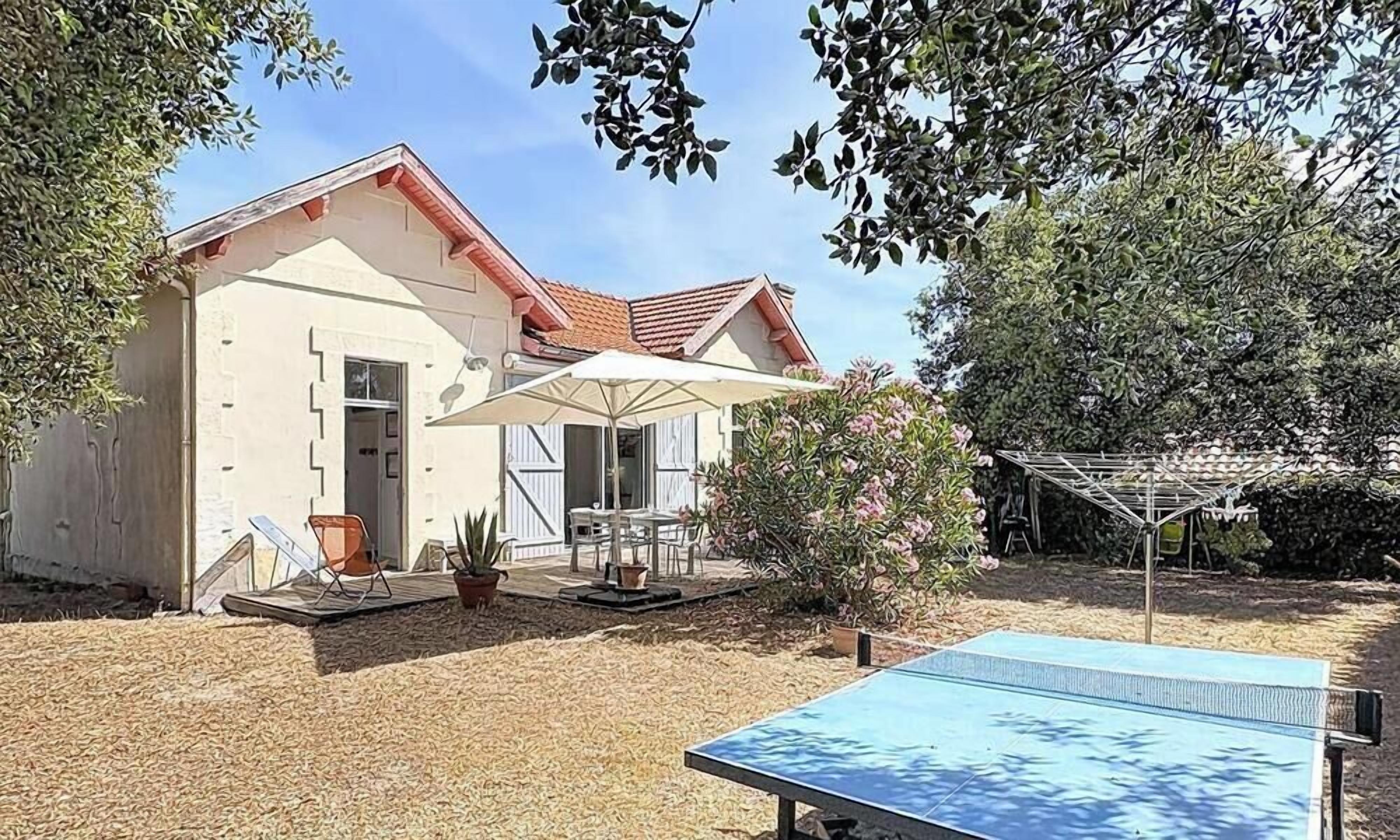 A house with a tennis court, outdoor seating, and a pergola.